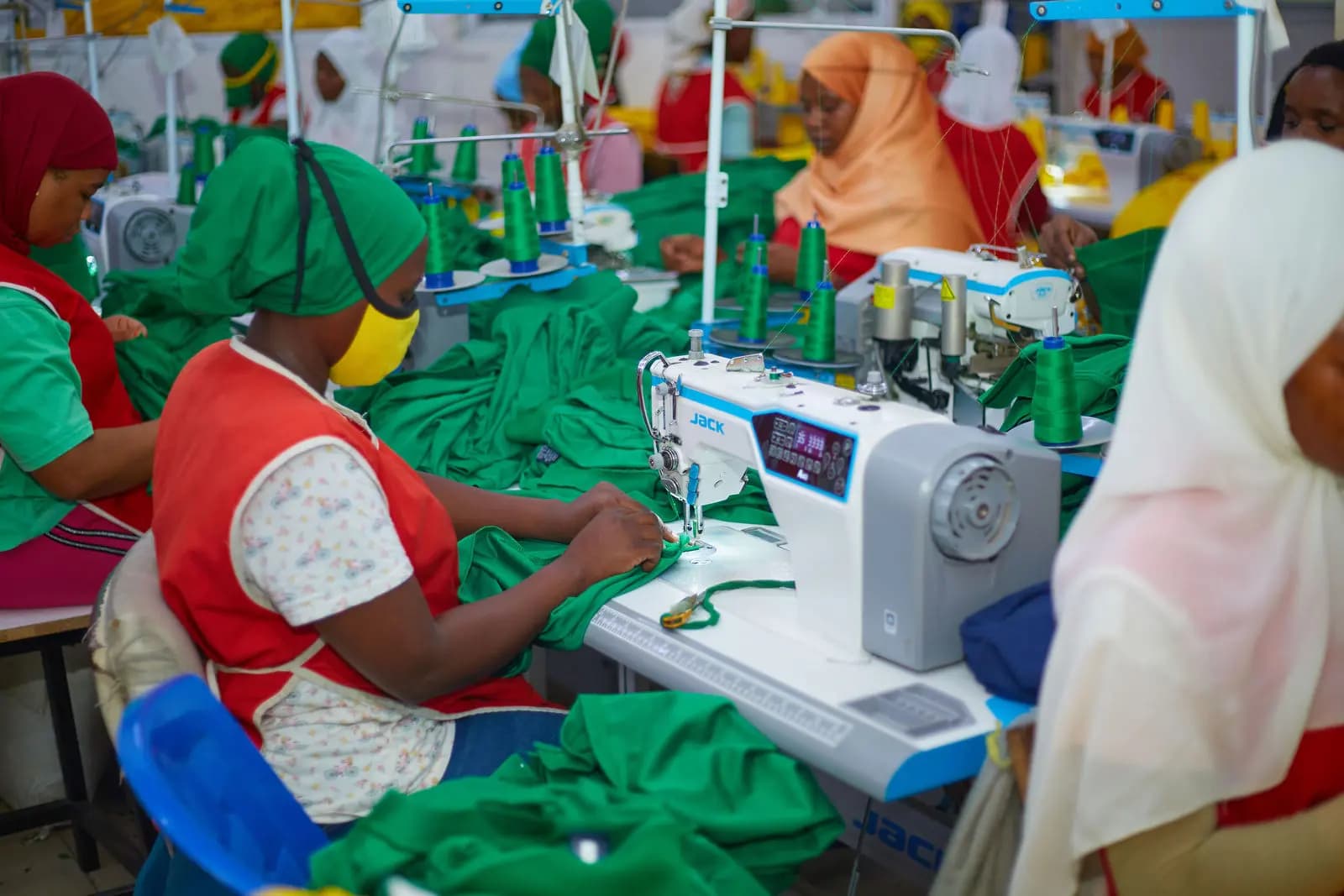 Machinists sewing green garments on the line at Swahili Knits